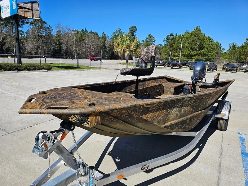 Slide: The Image of 2025 G3 Gator Tough 18 DK boat on trailer, camo design, parked outdoors. - 6