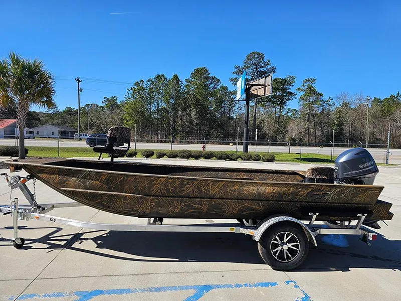 Slide: The Image of 2025 G3 Gator Tough 18 DK boat on trailer, camo design, parked outdoors. - 9