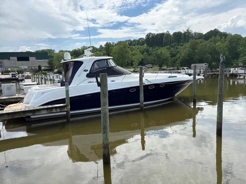 The Image of 2004 Sea Ray 460 Sundancer yacht docked in a marina, surrounded by calm water and lush greenery. - 0