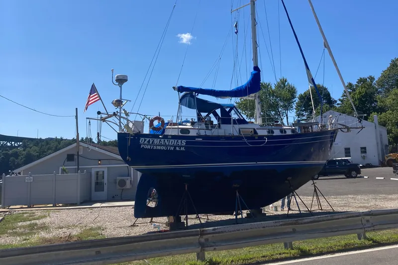 Slide: The Image of A 1978 Custom Fantasia C/C Double Ended Cutter sailboat on land, with an American flag. - 30