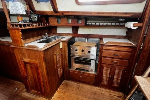 Slide: The Image of Wooden boat kitchen interior with sink, stove, and storage. Custom Fantasia C/C Double Ended Cutter, 1978. - 6