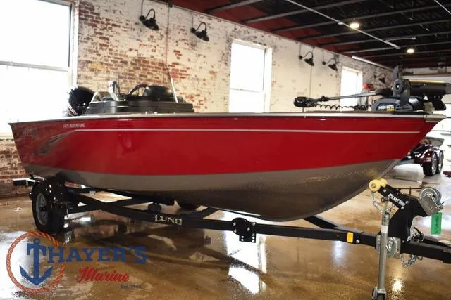 Slide: The Image of 2022 Lund 1675 Adventure Sport boat in a showroom, red exterior, on a trailer. - 1