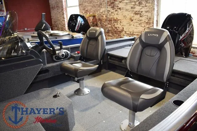 Slide: The Image of 2022 Lund 1675 Adventure Sport boat interior with two seats, steering wheel, and Thayer's Marine logo. - 10