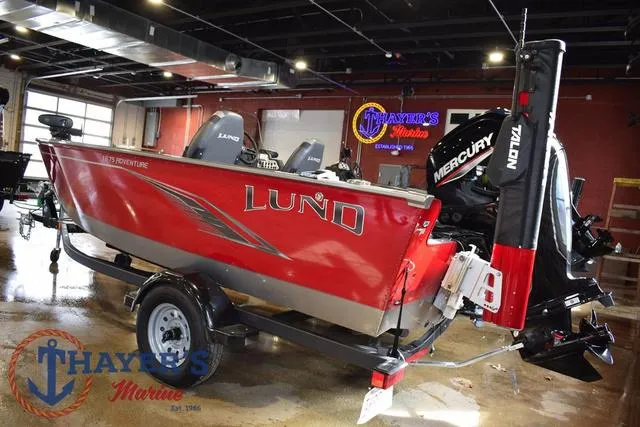 Slide: The Image of 2022 Lund 1675 Adventure Sport boat in showroom, featuring red exterior and Mercury engine. - 3