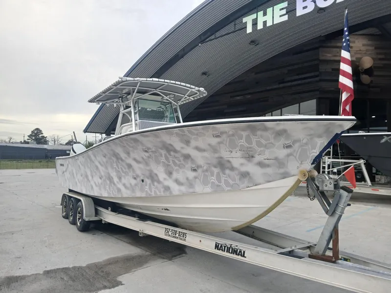 Slide: The Image of 2001 Regulator 32 boat on trailer, parked outside a modern building with American flag. - 13