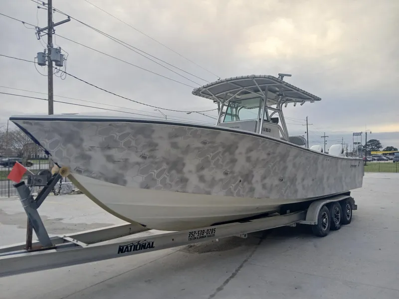 Slide: The Image of 2001 Regulator 32 boat on trailer, featuring a camouflage pattern, parked outdoors. - 14