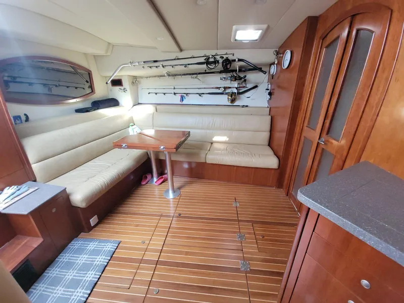 Slide: The Image of Interior of 2011 Rampage 41 Express boat with seating, fishing rods, and wooden flooring. - 14