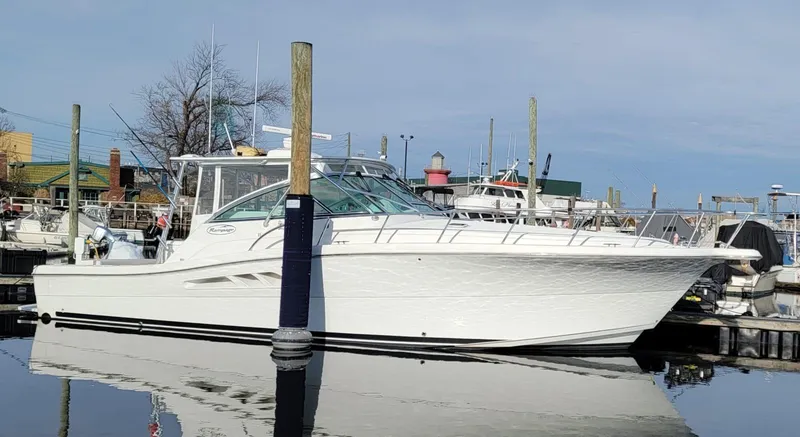 Slide: The Image of 2011 Rampage 41 Express boat docked in a marina, reflecting on calm water. - 2
