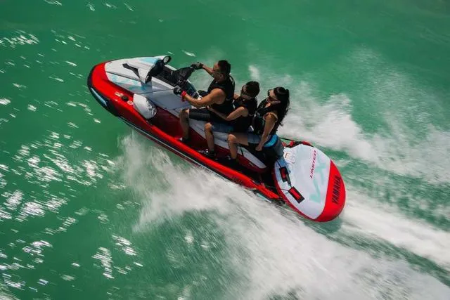 Slide: The Image of 2025 Yamaha Waverunner VX Limited speeding on turquoise water with three riders. - 18