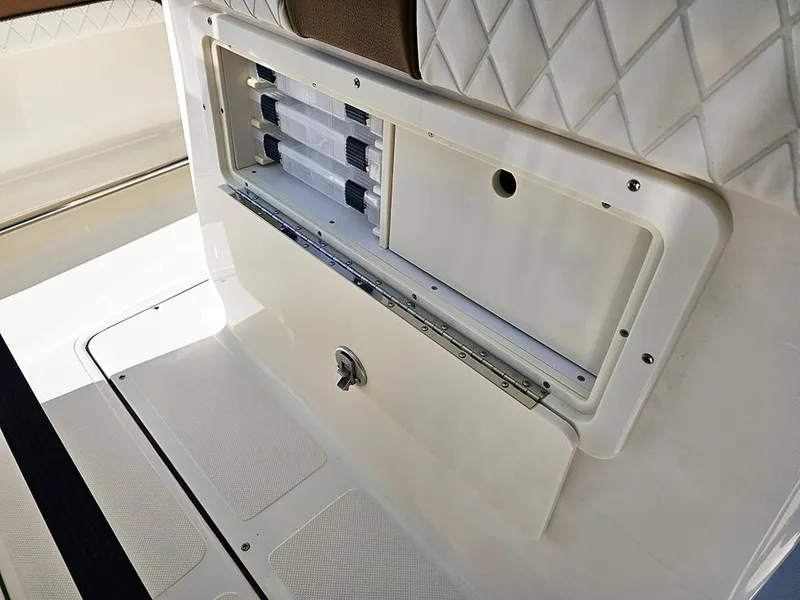 Slide: The Image of 2025 Pioneer 222 Sportfish boat storage compartment with quilted upholstery and secure latch. - 35