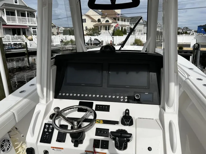 Slide: The Image of 2022 Regulator 34 boat dashboard with dual screens and steering wheel, docked near waterfront homes. - 5