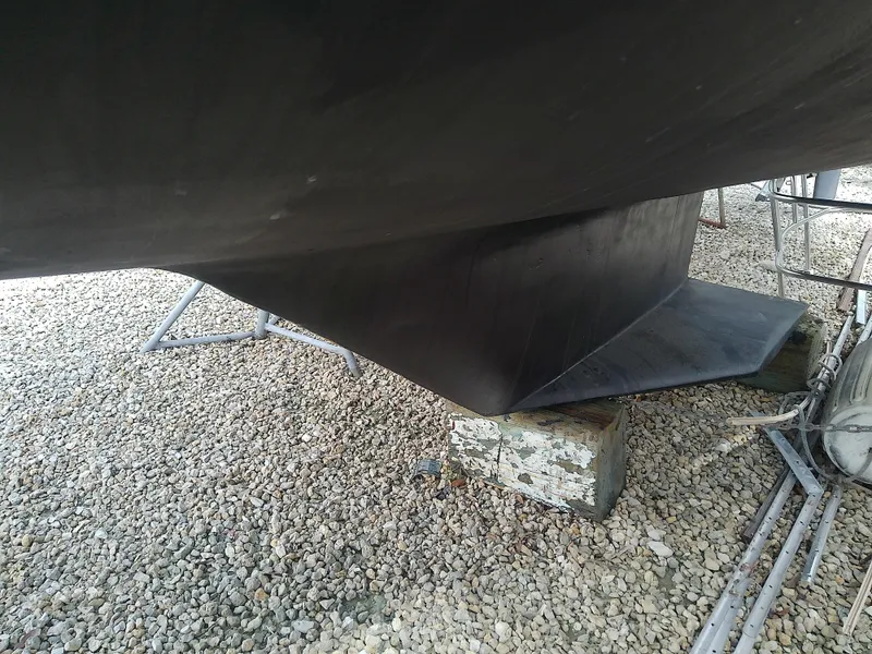 Slide: The Image of 1990 Catalina 30 MkII sailboat keel on gravel, supported by blocks. - 3