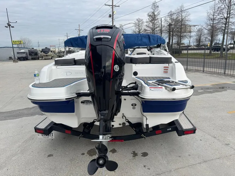 Slide: The Image of 2022 Tahoe 185 S boat with outboard motor on trailer, parked outdoors. - 5