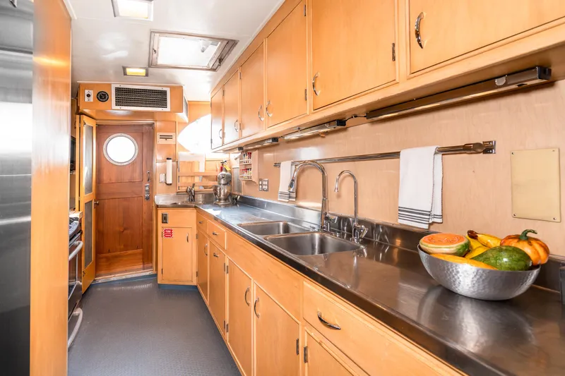 Slide: The Image of 1965 Burger Motoryacht kitchen with wooden cabinets, stainless steel countertops, and a fruit bowl. - 23