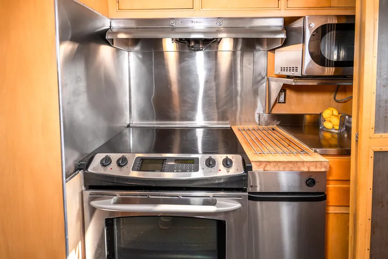 Slide: The Image of Modern kitchen in a 1965 Burger Motoryacht with stainless steel appliances and wooden cabinetry. - 25