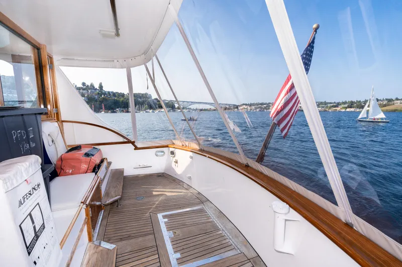 Slide: The Image of 1965 Burger Motoryacht deck with American flag, scenic water view, and sailboat in the distance. - 42