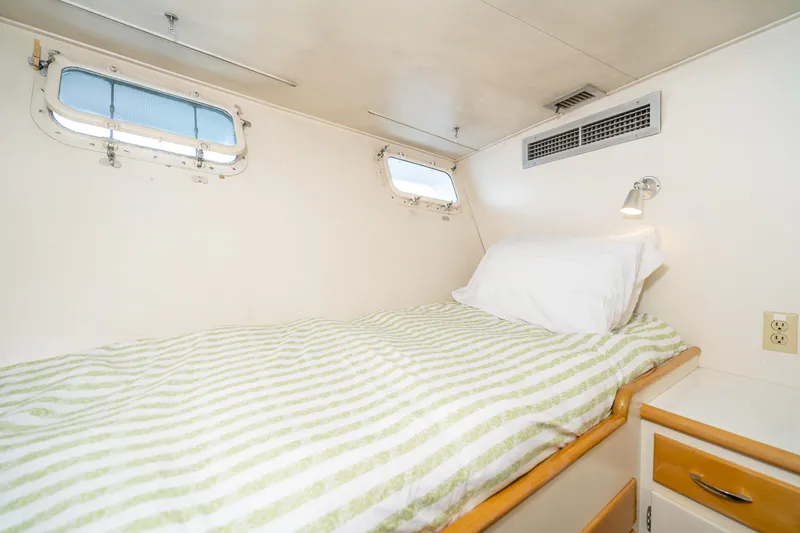 Slide: The Image of Cozy cabin bedroom in a 1965 Burger Motoryacht with striped bedding and porthole windows. - 44