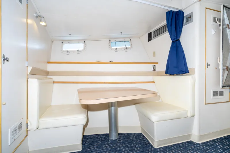 Slide: The Image of Cozy dining area in a 1965 Burger Motoryacht with blue curtains and white seating. - 48