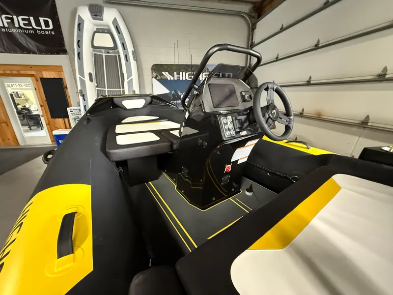 Slide: The Image of 2025 Highfield Velox 420 boat interior with steering console and seating in a showroom. - 3