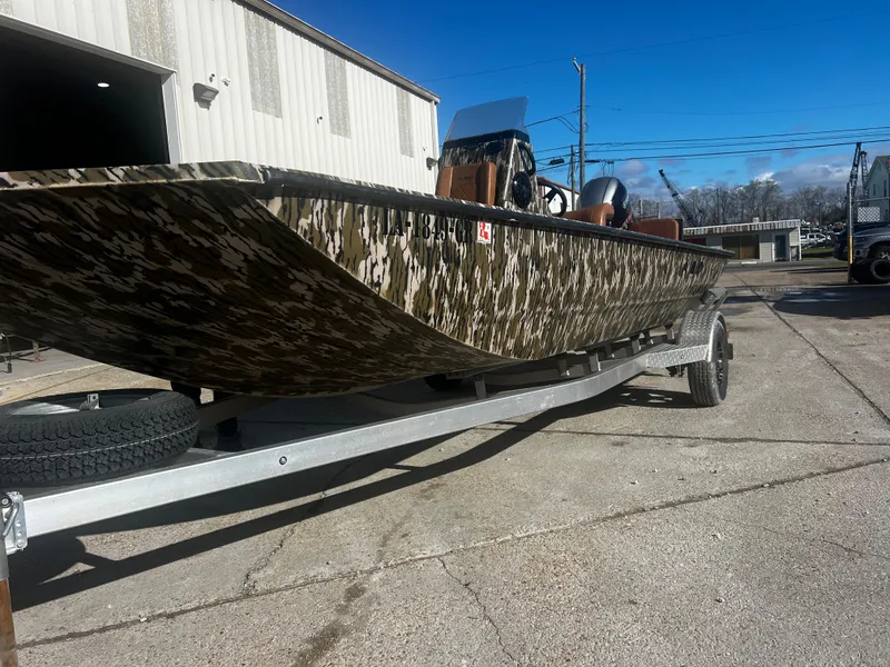 Slide: The Image of 2023 Avid 20 Rogue boat with camouflage design on a trailer, parked outdoors. - 4