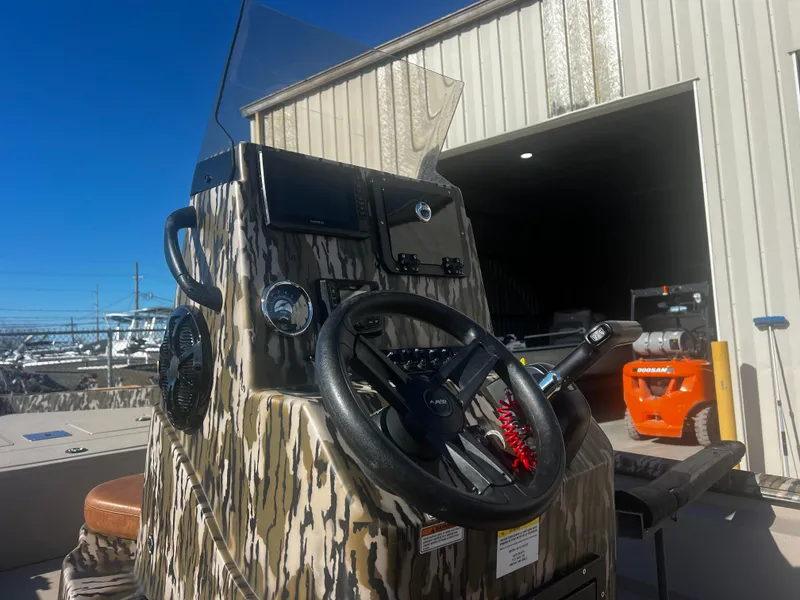 Slide: The Image of 2023 Avid 20 Rogue boat console with camouflage design, steering wheel, and controls. - 7