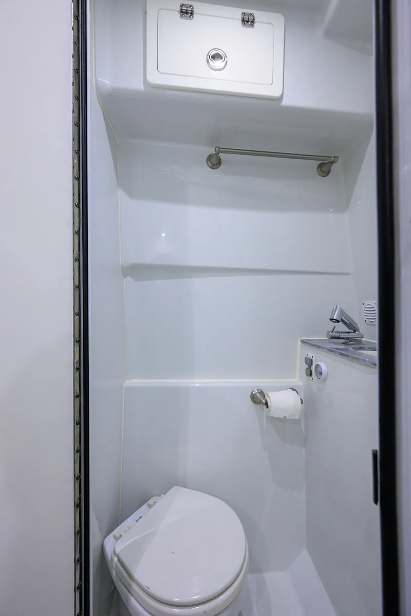 Slide: The Image of 2022 Contender 44FA boat bathroom with toilet, storage, and towel rack. - 45
