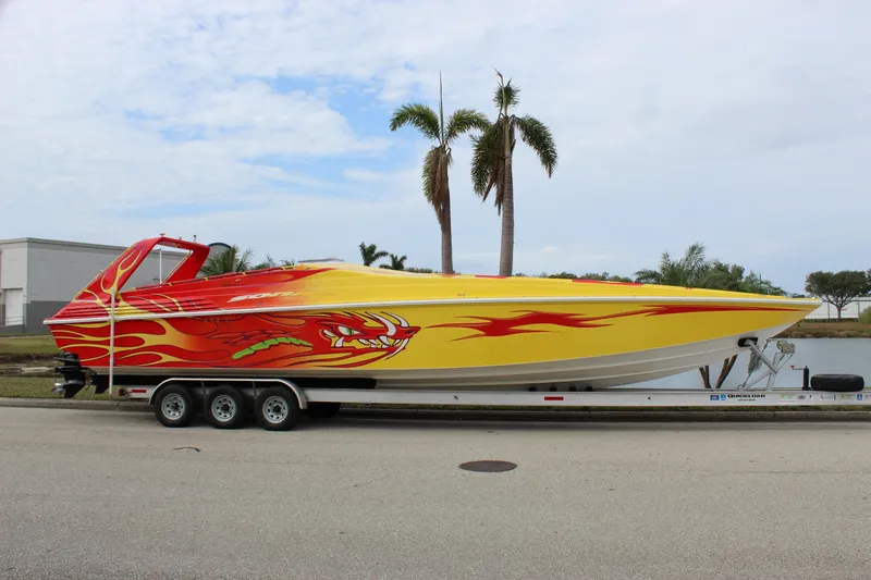 Slide: The Image of 2001 Sonic 42 SS speedboat with vibrant flame design on a trailer, parked near palm trees. - 12