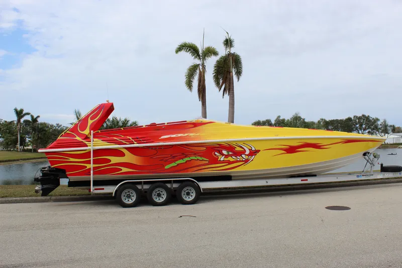 Slide: The Image of 2001 Sonic 42 SS speedboat with vibrant flame design on a trailer, parked near palm trees. - 13