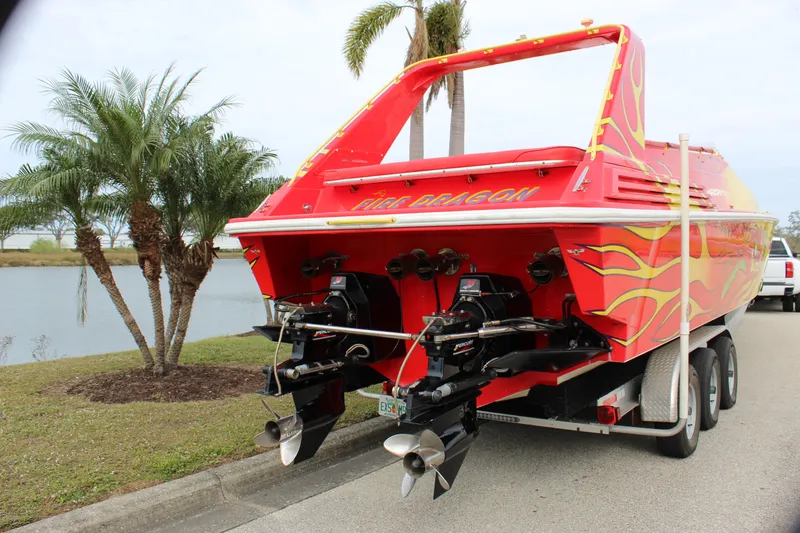 Slide: The Image of Red 2001 Sonic 42 SS speedboat with flame design on trailer, parked near palm trees. - 16