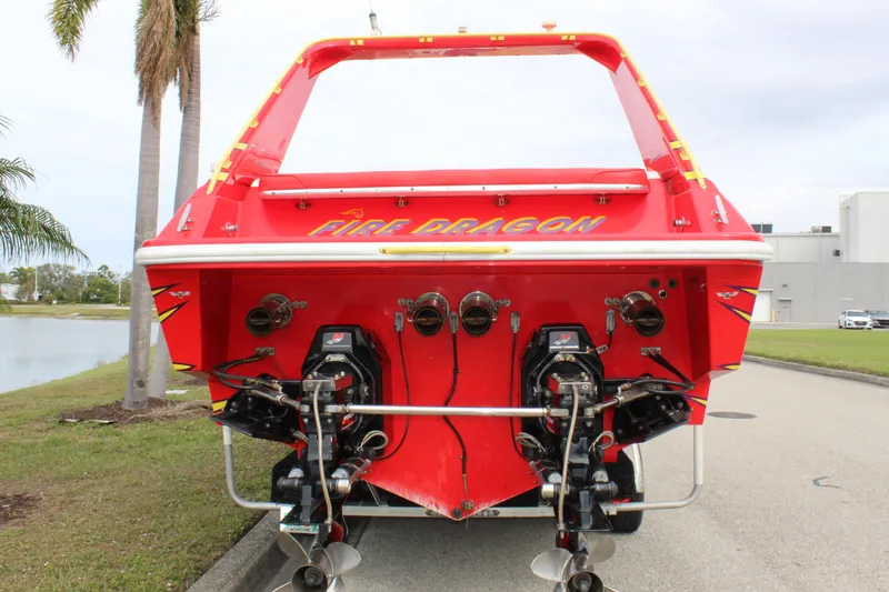 Slide: The Image of Red 2001 Sonic 42 SS boat named "Fire Dragon" with dual engines, parked near palm trees. - 17