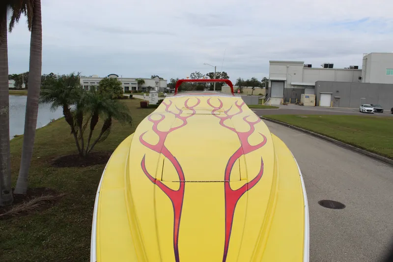 Slide: The Image of Yellow 2001 Sonic 42 SS boat with red flame design, parked near palm trees and industrial buildings. - 22