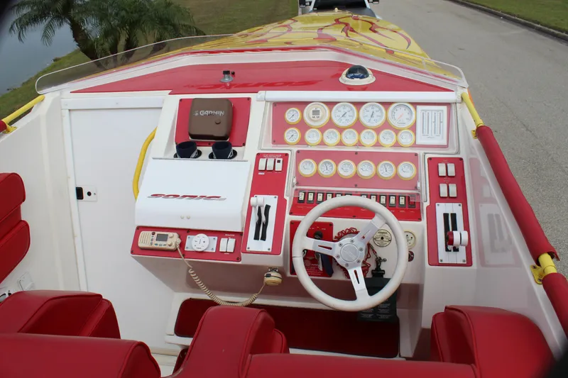 Slide: The Image of 2001 Sonic 42 SS boat dashboard with red and white interior, steering wheel, and control gauges. - 34