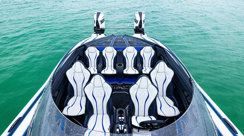 Slide: The Image of 2023 MTI 440X boat interior with white and blue seats on green water. - 13