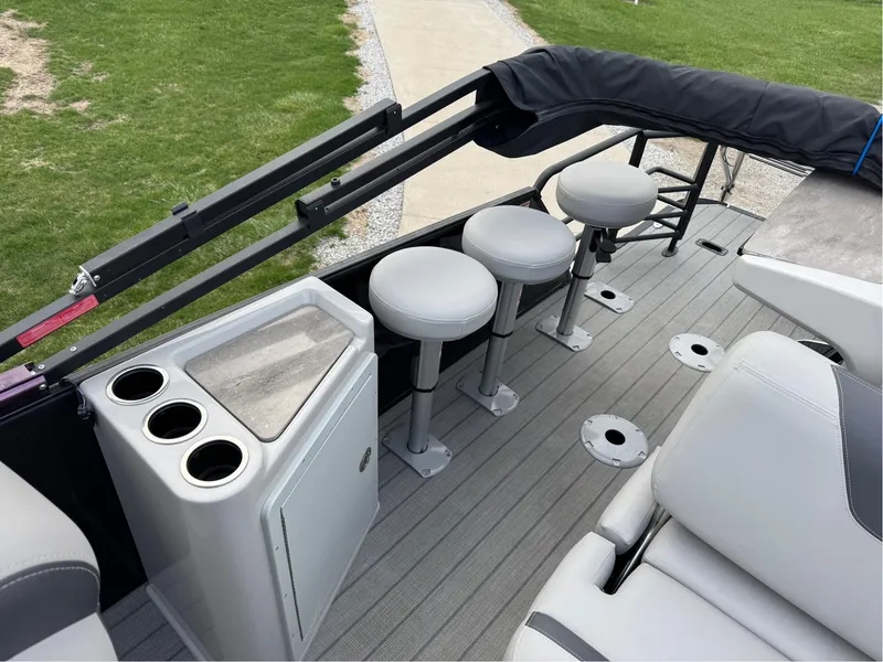 Slide: The Image of 2023 Sylvan L5 DLZ Bar pontoon boat interior with bar stools and cup holders. - 11