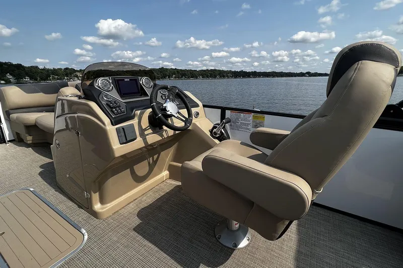 Slide: The Image of 2023 Sylvan L5 DLZ Bar boat interior with captain's chair and control panel on a lake. - 31