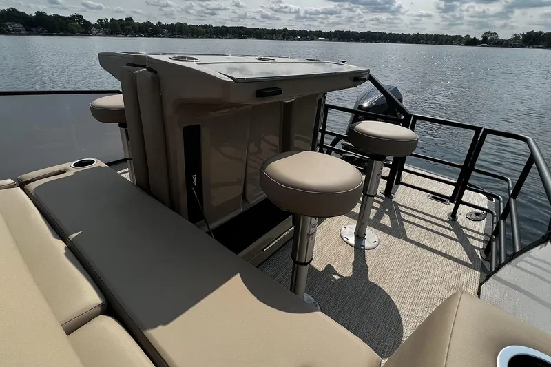 Slide: The Image of 2023 Sylvan L5 DLZ Bar pontoon boat with bar stools on a serene lake. - 38