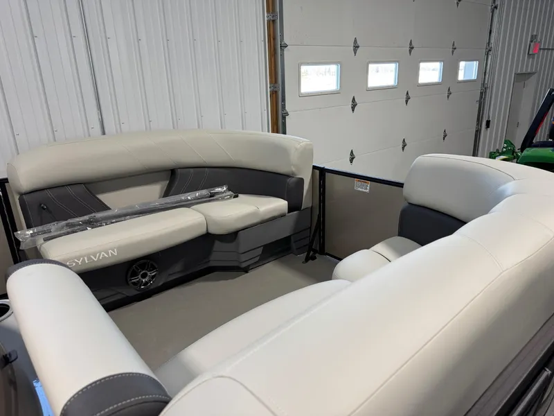 Slide: The Image of 2024 Sylvan MIRAGE 820 LZ boat interior with plush seating in a garage setting. - 9