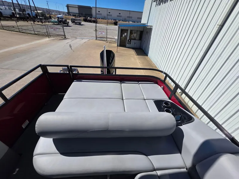 Slide: The Image of 2023 Regency 250 DL3 boat with spacious seating and cup holders, docked near a warehouse. - 4