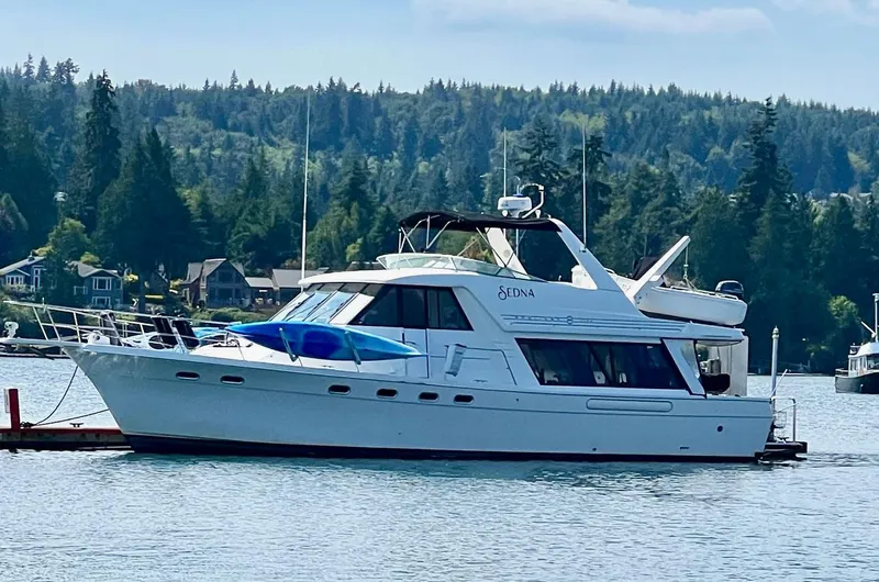 Slide: The Image of Bayliner 4788 Pilothouse 1996 yacht docked on serene lake with forested background. - 2