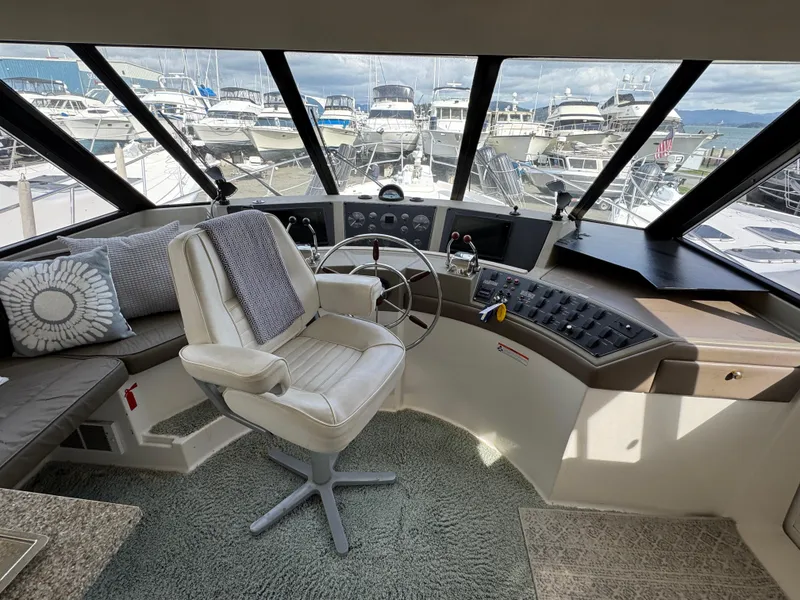 Slide: The Image of Interior of 1996 Bayliner 4788 Pilothouse with helm, steering wheel, and marina view. - 23