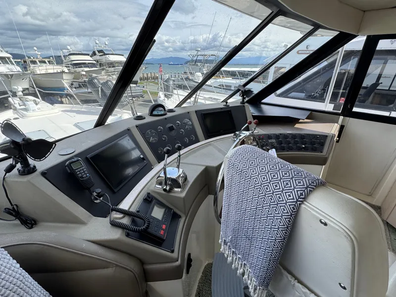 Slide: The Image of 1996 Bayliner 4788 Pilothouse interior with helm, controls, and marina view. - 24