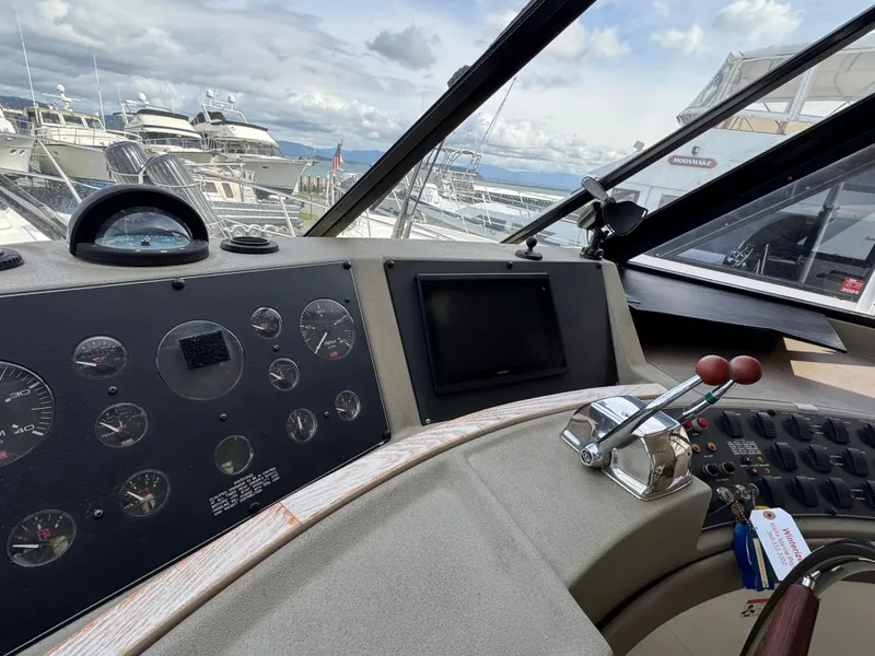Slide: The Image of 1996 Bayliner 4788 Pilothouse helm with gauges, controls, and marina view. - 25