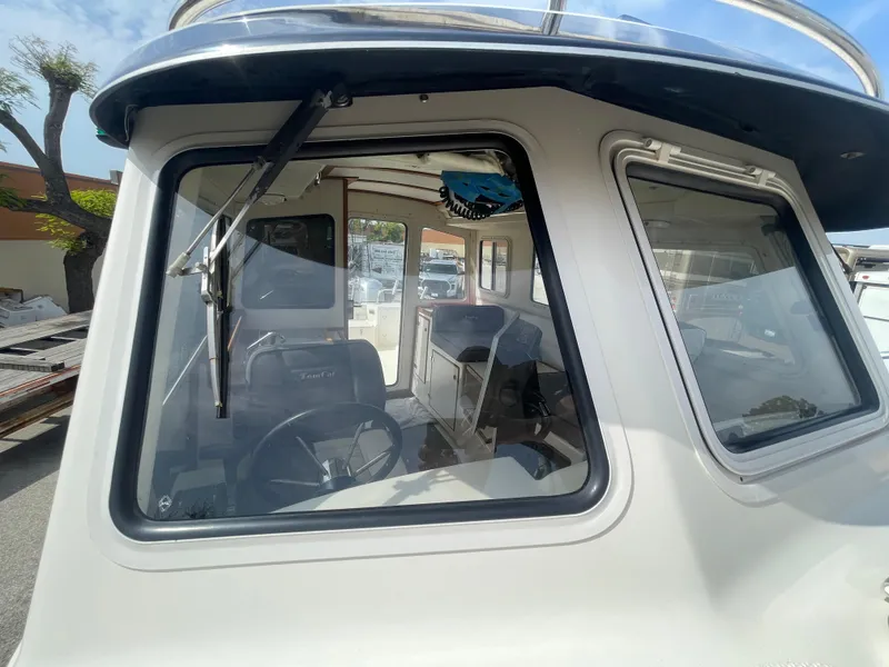 Slide: The Image of 2009 C-Dory TOMCAT 255 boat cabin with large windows and visible interior. - 18