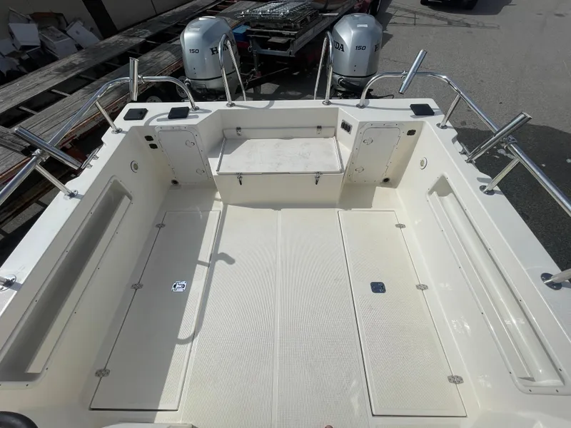Slide: The Image of 2009 C-Dory TOMCAT 255 boat deck with dual engines, spacious seating, and storage compartments. - 19