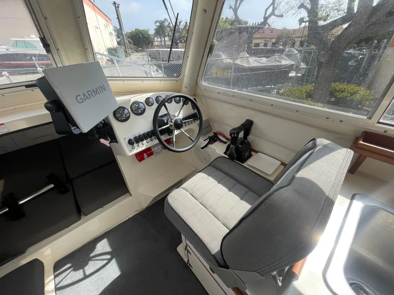 Slide: The Image of 2009 C-Dory TOMCAT 255 interior with Garmin navigation, steering wheel, and cushioned seating. - 22