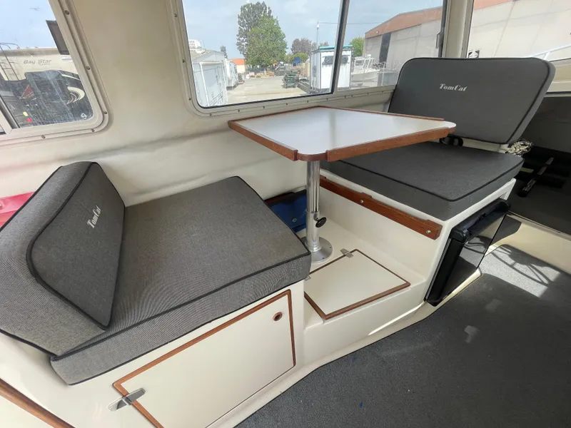 Slide: The Image of 2009 C-Dory TOMCAT 255 interior with seating and table, featuring gray cushions. - 31