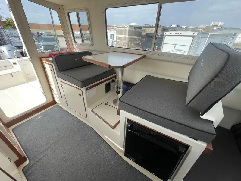 Slide: The Image of 2009 C-Dory TOMCAT 255 interior with seating and table, featuring large windows. - 32