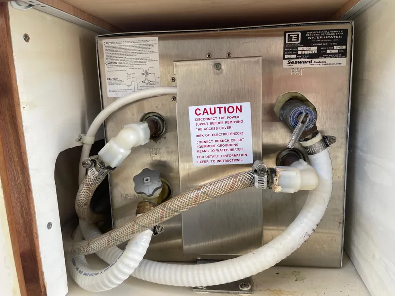 Slide: The Image of 2009 C-Dory TOMCAT 255 boat water heater with caution label and connected hoses. - 34