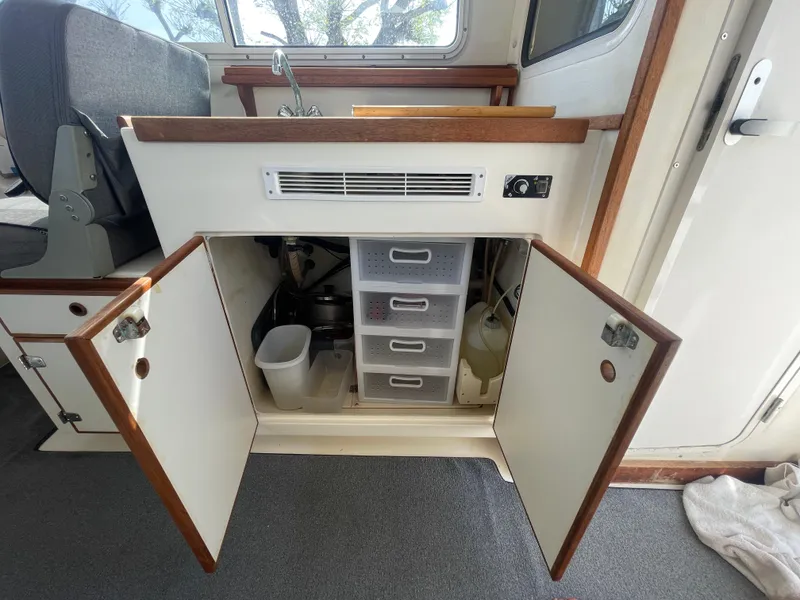 Slide: The Image of 2009 C-Dory TOMCAT 255 interior with open cabinet, storage drawers, and sink area. - 36