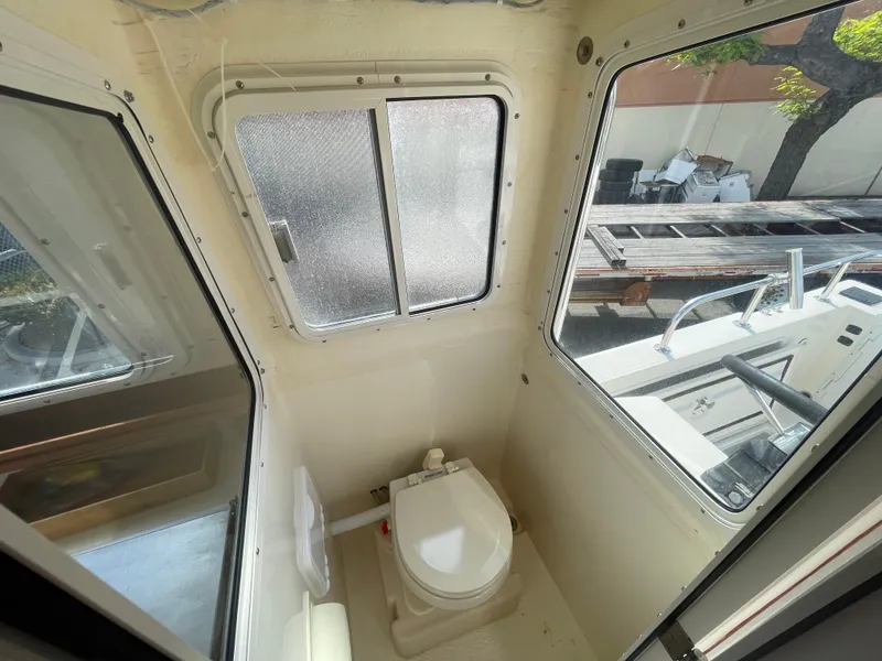 Slide: The Image of 2009 C-Dory TOMCAT 255 boat interior with compact marine toilet and windows. - 43